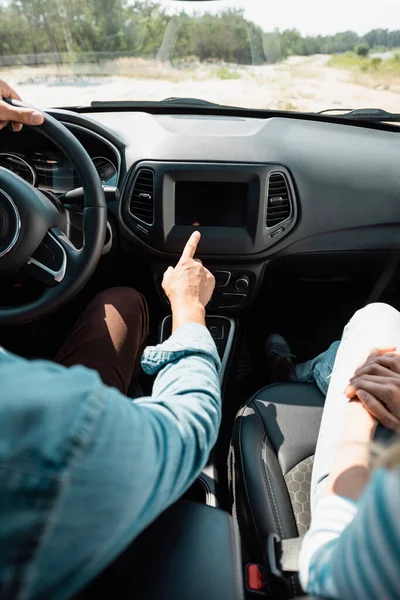 Обрезанный вид мужчины, указывающего пальцем во время вождения автомобиля рядом с женой — стоковое фото