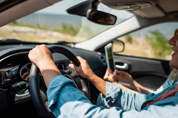 Enfoque selectivo del hombre que conduce el coche cerca de esposa con la tableta digital - foto de stock