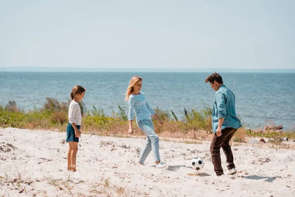Foco seletivo de pais com filha jogando futebol na praia — Fotografia de Stock