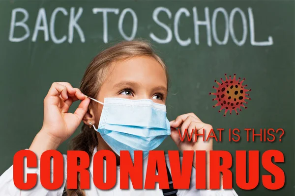 Foco seletivo de estudante usando máscara médica perto de quadro-negro, o que é esta inscrição coronavírus e ilustração de vírus — Fotografia de Stock
