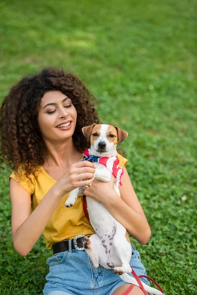 Foco seletivo da jovem mostrando o cão na câmera com bandana bandeira americana — Fotografia de Stock