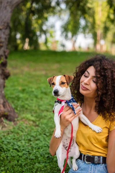 Foco seletivo de jovem segurando cão vestindo bandana bandeira americana — Fotografia de Stock