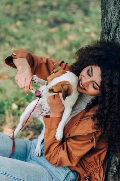 Focus selettivo della donna in abito autunno giocare con jack russell terrier nel parco — Foto stock