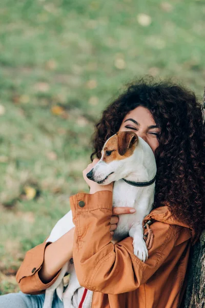 Selektiver Fokus der lockigen Frau, die Jack Russell Terrier im Freien hält — Stockfoto