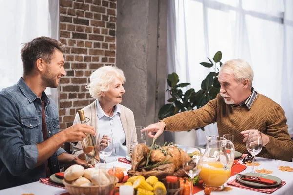 Homem sênior apontando com o dedo enquanto celebra ação de graças com a família na mesa servida — Fotografia de Stock