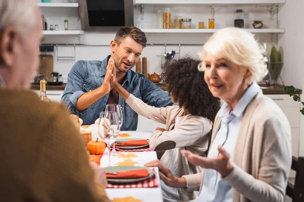 Homme donnant haute cinq à afro-américaine fille pendant thanksgiving dîner avec la famille — Photo de stock