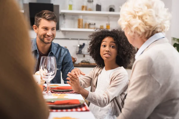 Foco seletivo da menina afro-americana gesticulando enquanto fala durante o jantar de ação de graças com a família — Fotografia de Stock