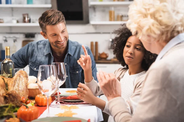 Foco seletivo da menina afro-americana mostrando gesto ideia enquanto celebra ação de graças com a família — Fotografia de Stock