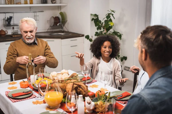 Selektiver Fokus des fröhlichen afrikanisch-amerikanischen Mädchens gestikulierend während des Dankeschön-Dinners mit der Familie — Stockfoto