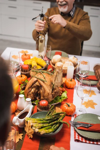 Селективное внимание старшего человека, открывающего бутылку белого вина во время ужина в честь Дня благодарения — стоковое фото