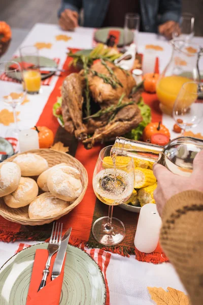 Abgeschnittene Ansicht des älteren Mannes schenkt Weißwein in der Nähe köstliches Abendessen zum Erntedankfest serviert — Stockfoto