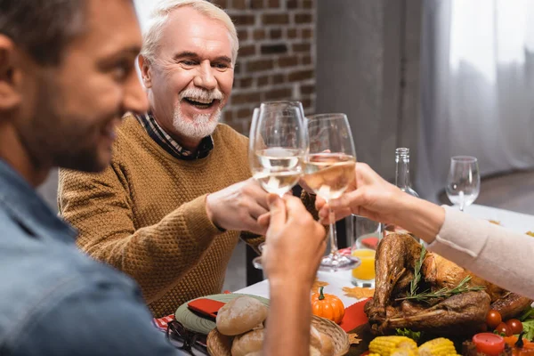 Fuoco selettivo di gioioso uomo anziano clinking bicchieri di vino con la famiglia il giorno del Ringraziamento — Foto stock