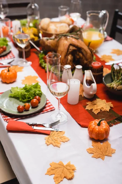 Селективный акцент стола подается с традиционным праздничным ужином, украшенным листьями, свечами и тыквами — стоковое фото