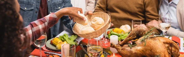 Panoramic crop of african american girl taking bun from wicker bowl — Stock Photo