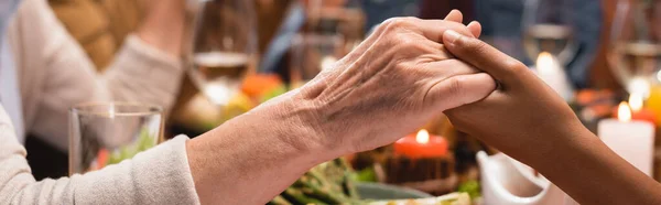 Panoramic crop of african american girl and senior woman holding hands on thanksgiving — Stock Photo