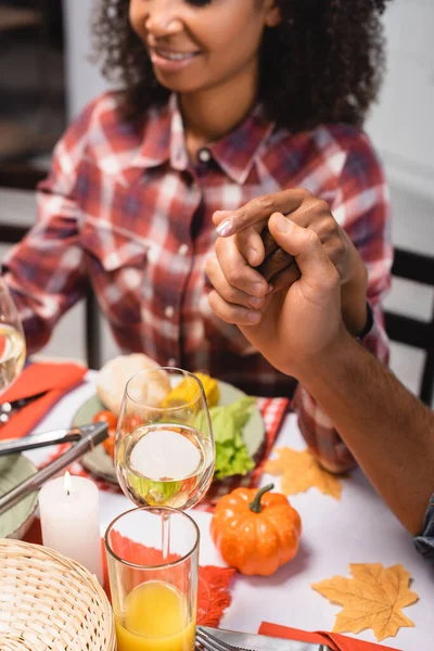 Vista recortada hombre y mujer afroamericana tomados de la mano cerca de la cena en acción de gracias - foto de stock