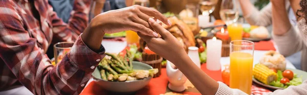 Ausgeschnittene Ansicht einer afrikanisch-amerikanischen Mutter und Tochter, die sich beim Danksagungsessen an den Händen halten, horizontales Bild — Stockfoto