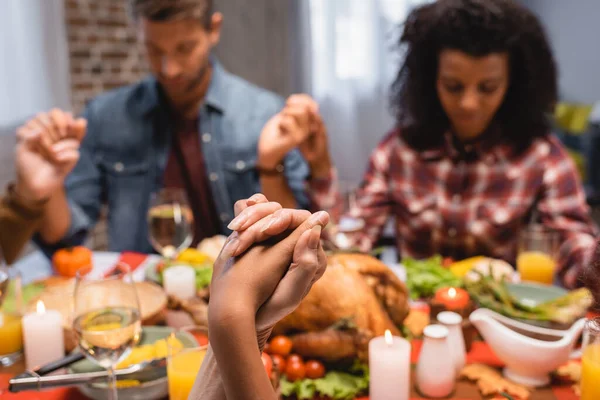 Selective focus of multiethnic family with closed eyes holding hands on thanksgiving — Stock Photo