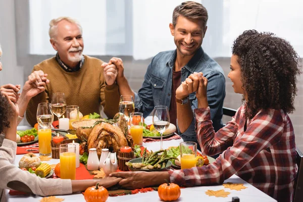 Men looking at african american woman while holding hands on thanksgiving — Stock Photo