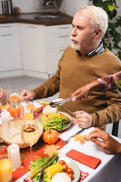 Selektiver Fokus einer afrikanisch-amerikanischen Frau, die beim Erntedank-Dinner Gemüse in der Nähe eines älteren Mannes serviert — Stockfoto