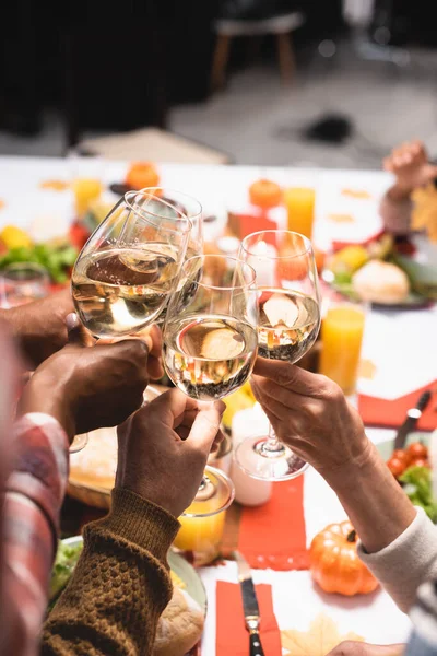 Partial view of multiethnic family clinking glasses of red wine during thanksgiving celebration — Stock Photo