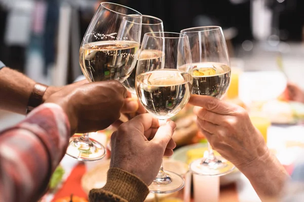 Cropped view of multicultural relatives clinking wine glasses during thanksgiving dinner — Stock Photo