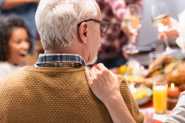 Focus selettivo della donna anziana che abbraccia il marito mentre celebra il Ringraziamento con la famiglia — Foto stock