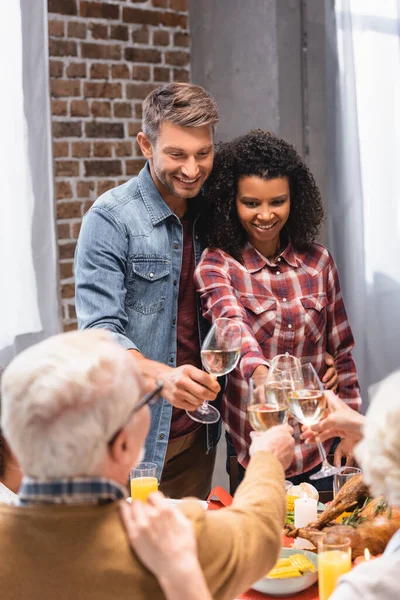 Selektiver Schwerpunkt multikultureller Familienschmaus mit Wein in der Nähe schmackhafter Truthähne auf dem Tisch — Stockfoto