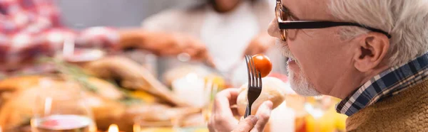 Aussichtsreiche Ernte: Senior isst Kirschtomate bei Erntedankfeier — Stockfoto