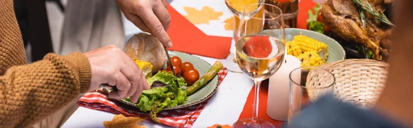 Панорамный снимок пожилого человека, режущего салат во время ужина в честь Дня благодарения — стоковое фото