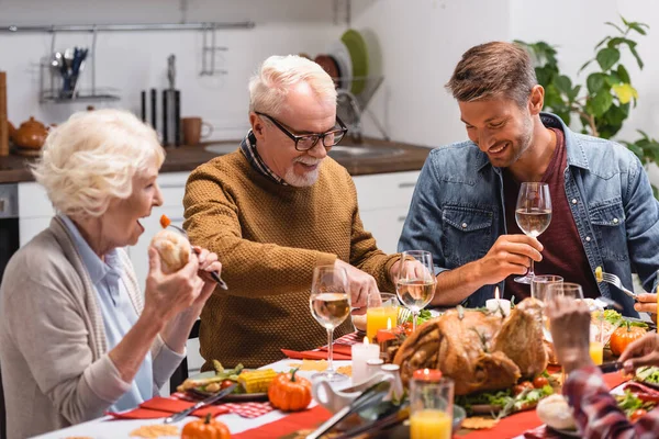 Focus selettivo dell'uomo che tiene il vino vicino alla famiglia e alla figlia durante il Ringraziamento — Foto stock