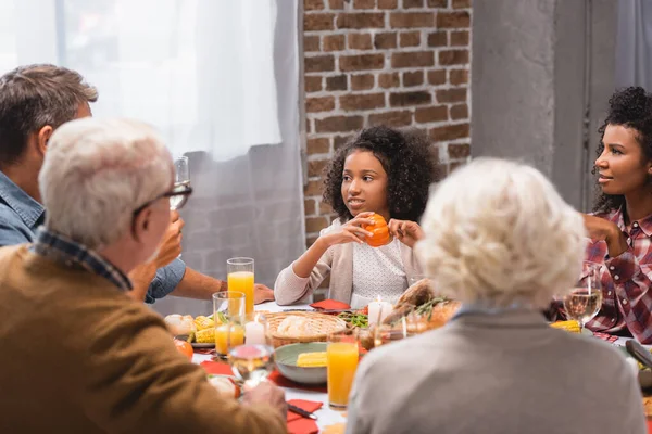 Selective focus of african american kid holding pumpkin near parents and grandparents during celebration thanksgiving — Stock Photo