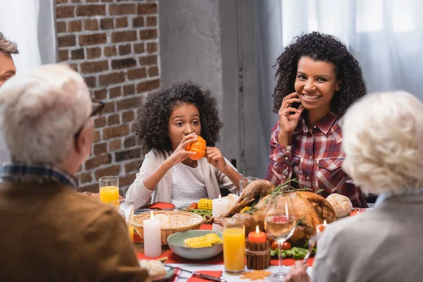 Selektiver Fokus einer afrikanisch-amerikanischen Frau, die neben Tochter und Familie sitzt, während sie Erntedank feiert — Stockfoto