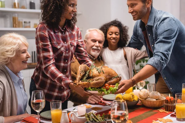 Concentration sélective de la femme afro-américaine donnant la dinde au mari près de la famille pendant le dîner de Thanksgiving — Photo de stock