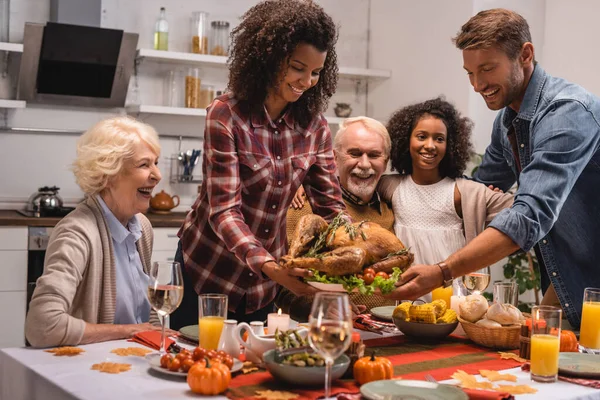 Concentration sélective de la famille multiethnique debout près de la dinde et dîner d'action de grâce à la maison — Stock Photo