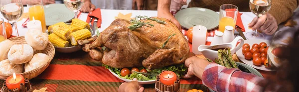 Horizontales Bild einer afrikanisch-amerikanischen Frau, die beim Erntedankessen Truthahn in der Nähe ihrer Familie auf den Tisch legt — Stockfoto