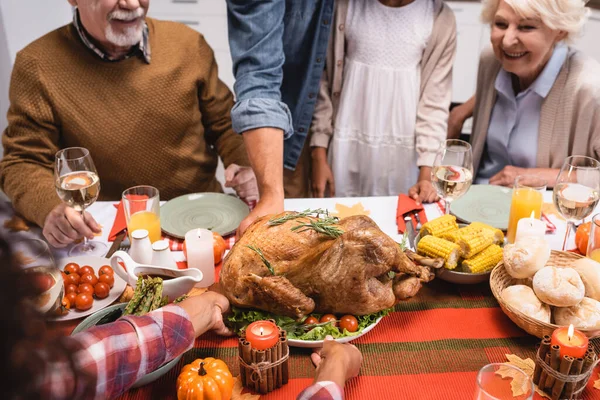 Enfoque selectivo de la mujer afroamericana poniendo pavo en la mesa cerca de la familia y la cena de acción de gracias - foto de stock