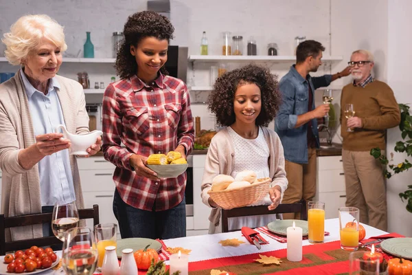 Concentration sélective de l'enfant afro-américain tenant des petits pains près des parents pendant le dîner d'action de grâce à la maison — Photo de stock