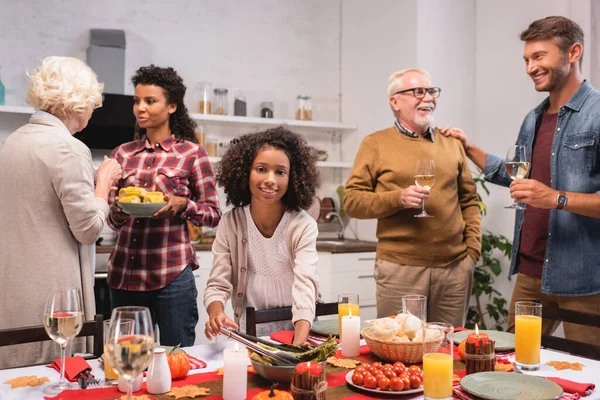 Selective focus of african american kid standing near parents and food on table during thanksgiving dinner — Stock Photo