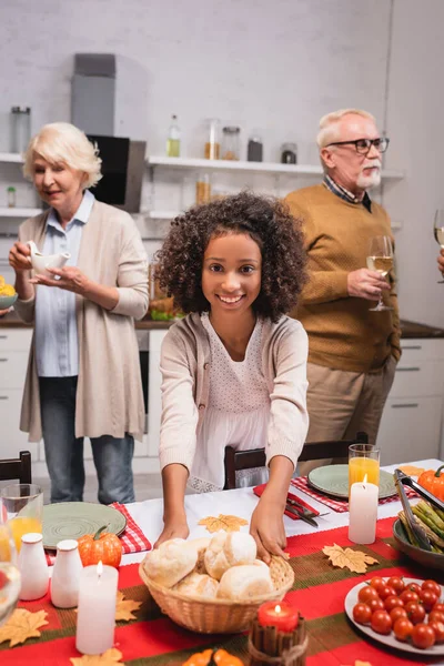 Focus selettivo della ragazza afro-americana che tiene i panini vicino ai nonni durante il Ringraziamento — Foto stock