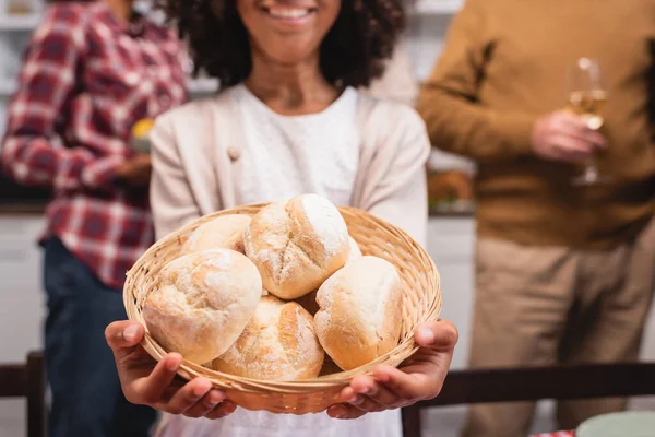Cropped view of african american girl holding basket with buns near parents at home — Stock Photo