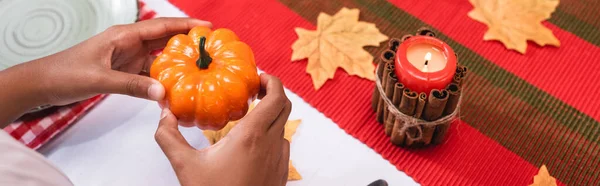 Panoramic shot of african american girl holding decorative pumpkin near candle during thanksgiving — Stock Photo