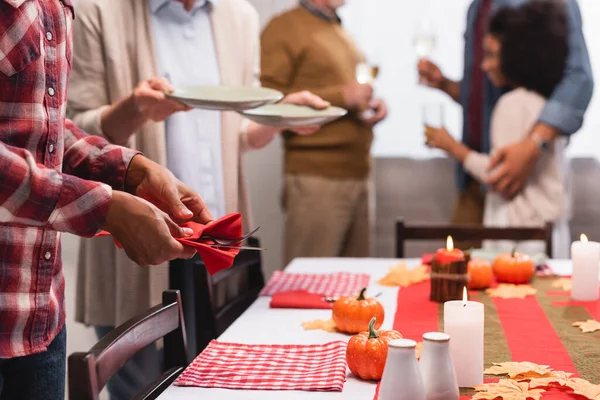 Selective focus of multiethnic women serving table with thanksgiving decorations — Stock Photo