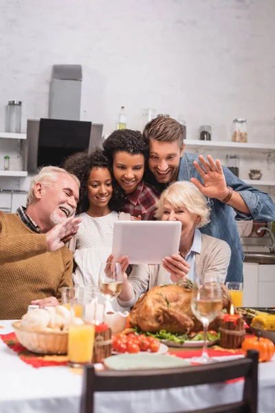 Селективный фокус многонациональной семьи, имеющей видеозвонок на цифровом планшете во время празднования Дня благодарения — стоковое фото