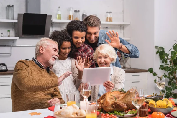 Focus selettivo della famiglia multiculturale che ondeggia sul tablet digitale durante la videochiamata e la celebrazione del Ringraziamento — Foto stock