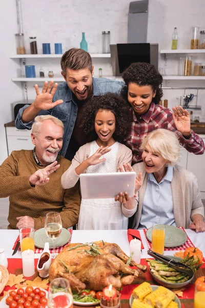 Selective focus of multicultural family gesturing during video call on digital tablet and thanksgiving celebration — Stock Photo