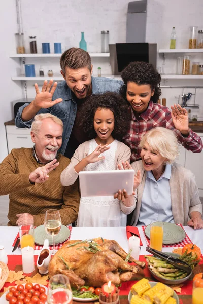 Enfoque selectivo del gesto familiar multicultural durante la videollamada en tabletas digitales y la celebración de Acción de Gracias - foto de stock