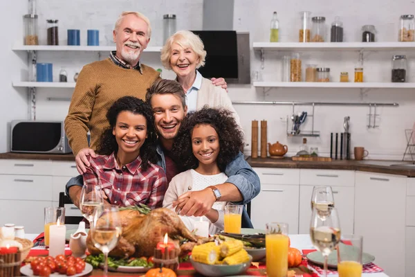 Enfoque selectivo de abrazos familiares multiculturales mientras se celebra el Día de Acción de Gracias en casa - foto de stock