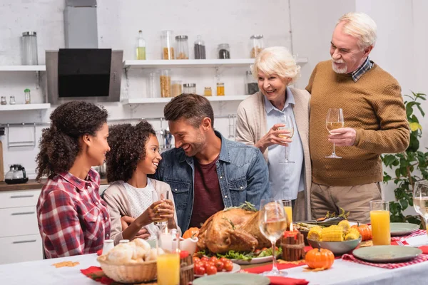 Selektiver Fokus der multikulturellen Familie, die Erntedank in der Nähe von Essen auf dem Tisch feiert — Stockfoto