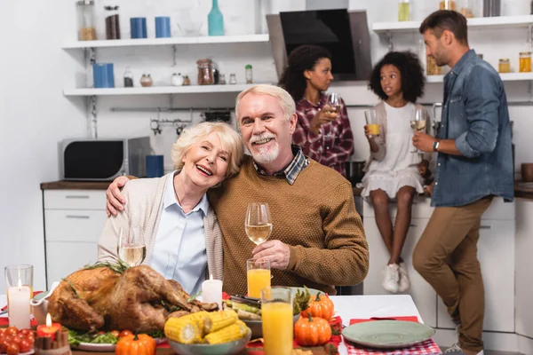 Selective focus of elderly man and woman with glasses of wine near food during thanksgiving celebration — Stock Photo